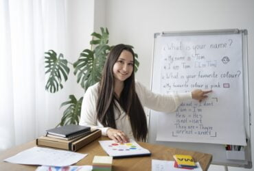 medium shot smiley teacher with whiteboard Praca ze znajomością języków obcych. Jakie są możliwości rozwoju?